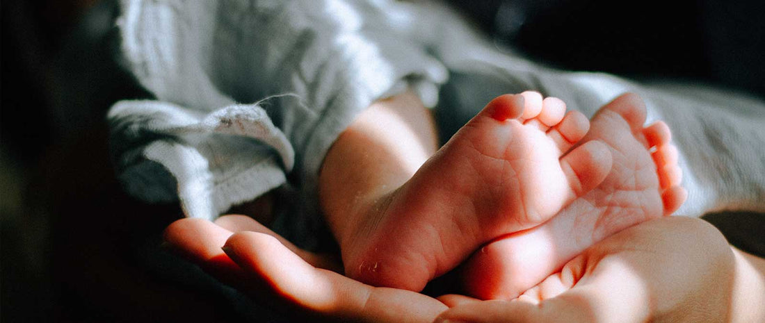 Infant being held in baby receiving blanket by adult